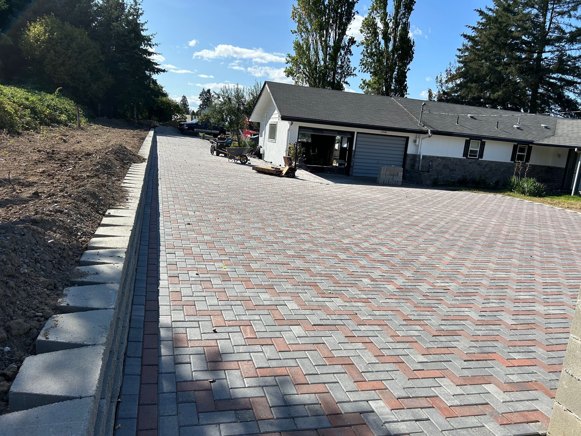 A brick driveway leading to a house with trees in the background