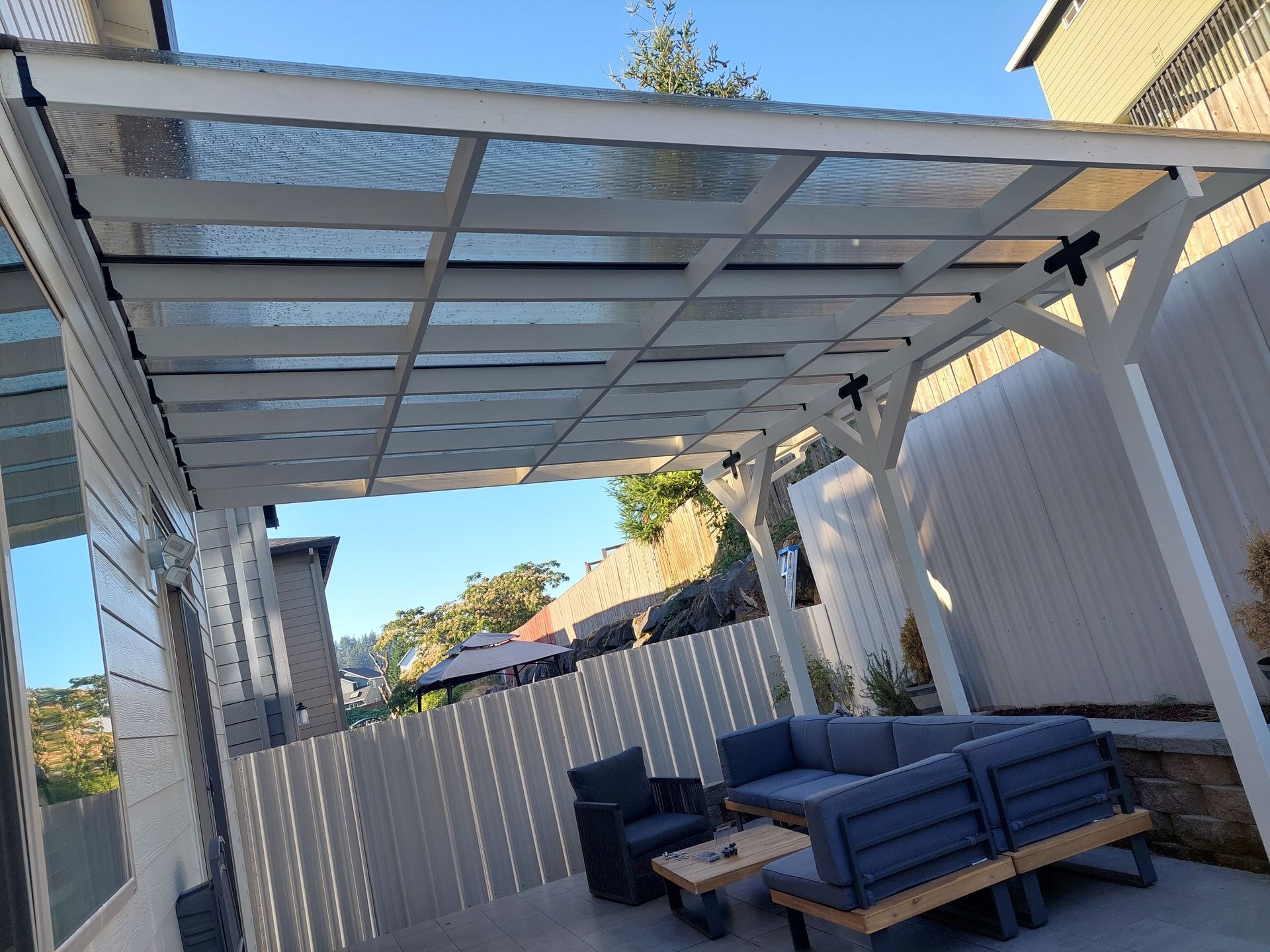 A patio with a couch , chairs and a table under a canopy.