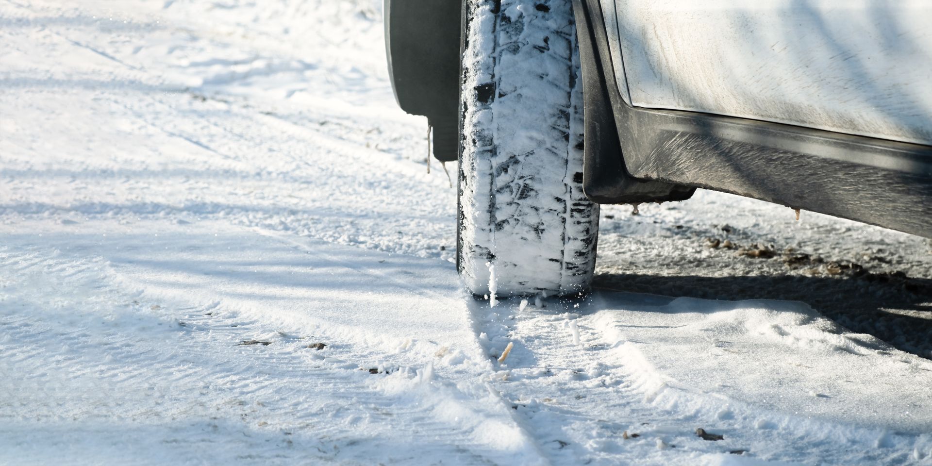 a car is driving through the snow on a snowy road .