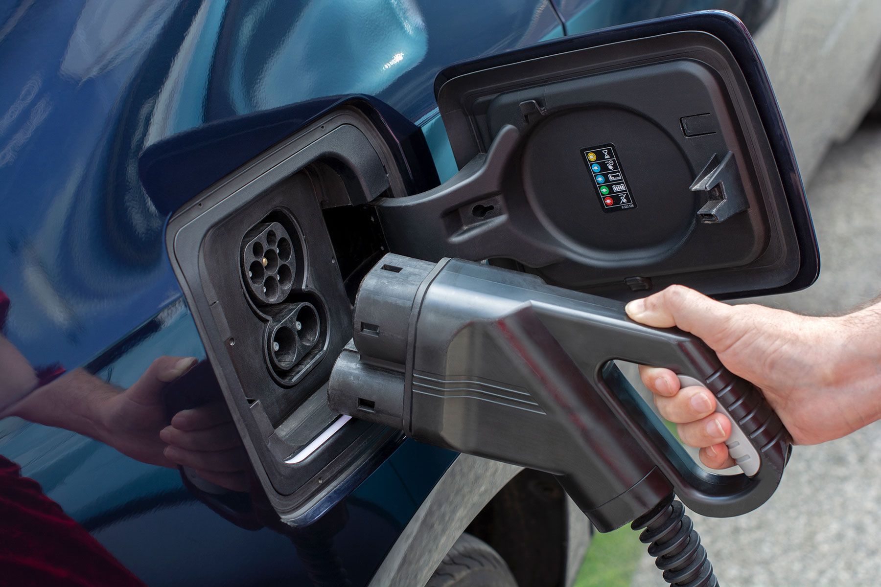 A person is plugging an electric car into a charging station.