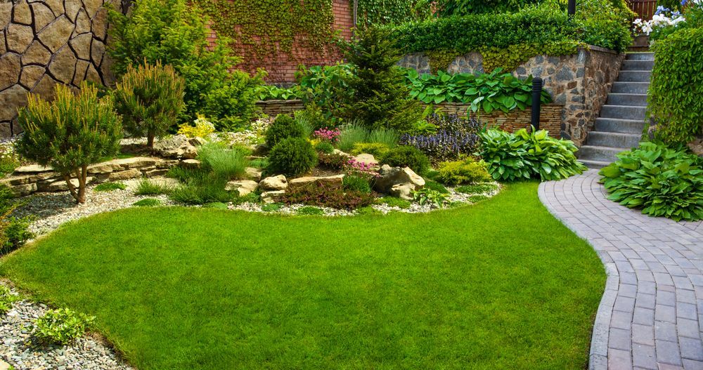 Lush green garden with stone pathways, tiered landscaping, and a variety of plants and shrubs.