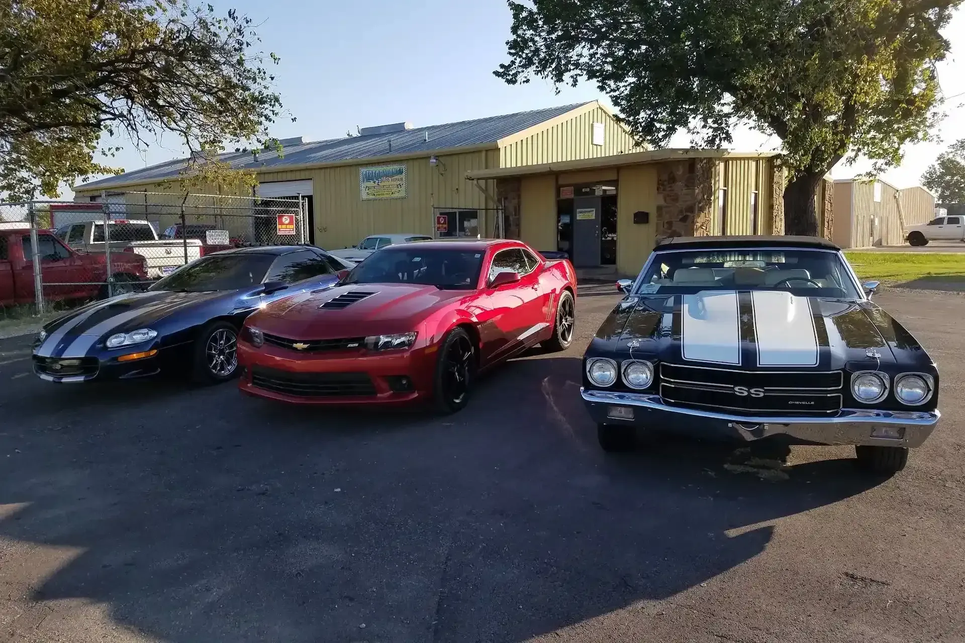 Three Chevrolet Camaros parked in front of a building with a red, black, and blue car. | Performance Auto Repair