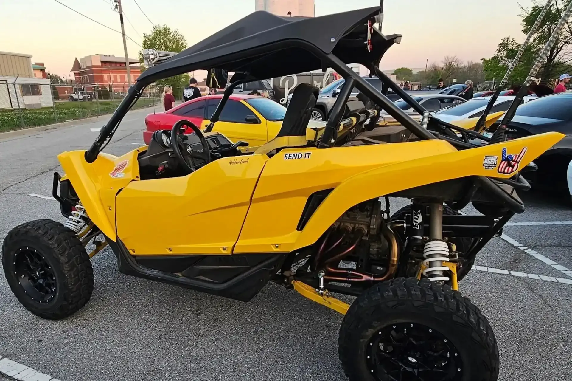 Yellow off-road vehicle with black cage roof parked in a lot; several cars in background. | Performance Auto Repair