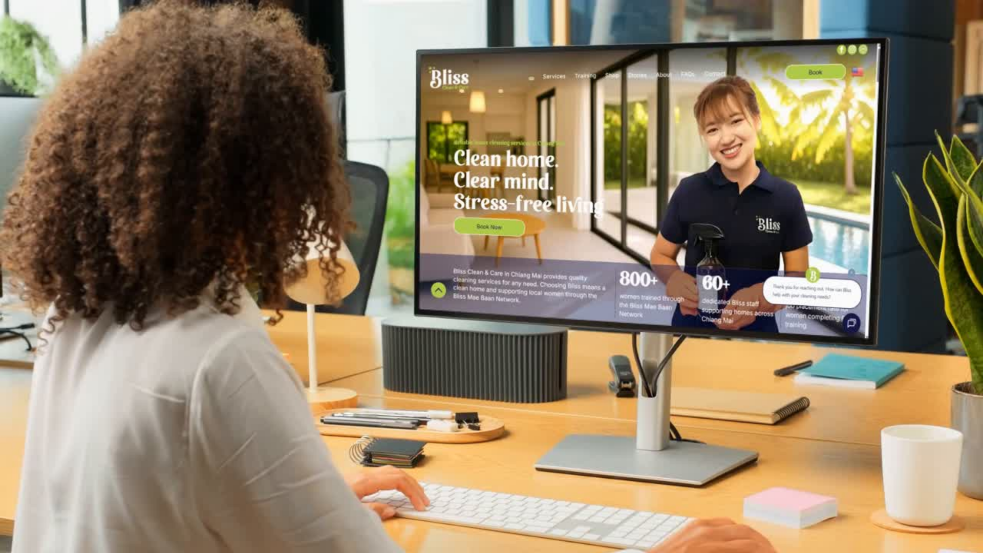 Woman using computer, seeing video of cleaner. Office setting, desk with keyboard, monitor displaying advertisement.
