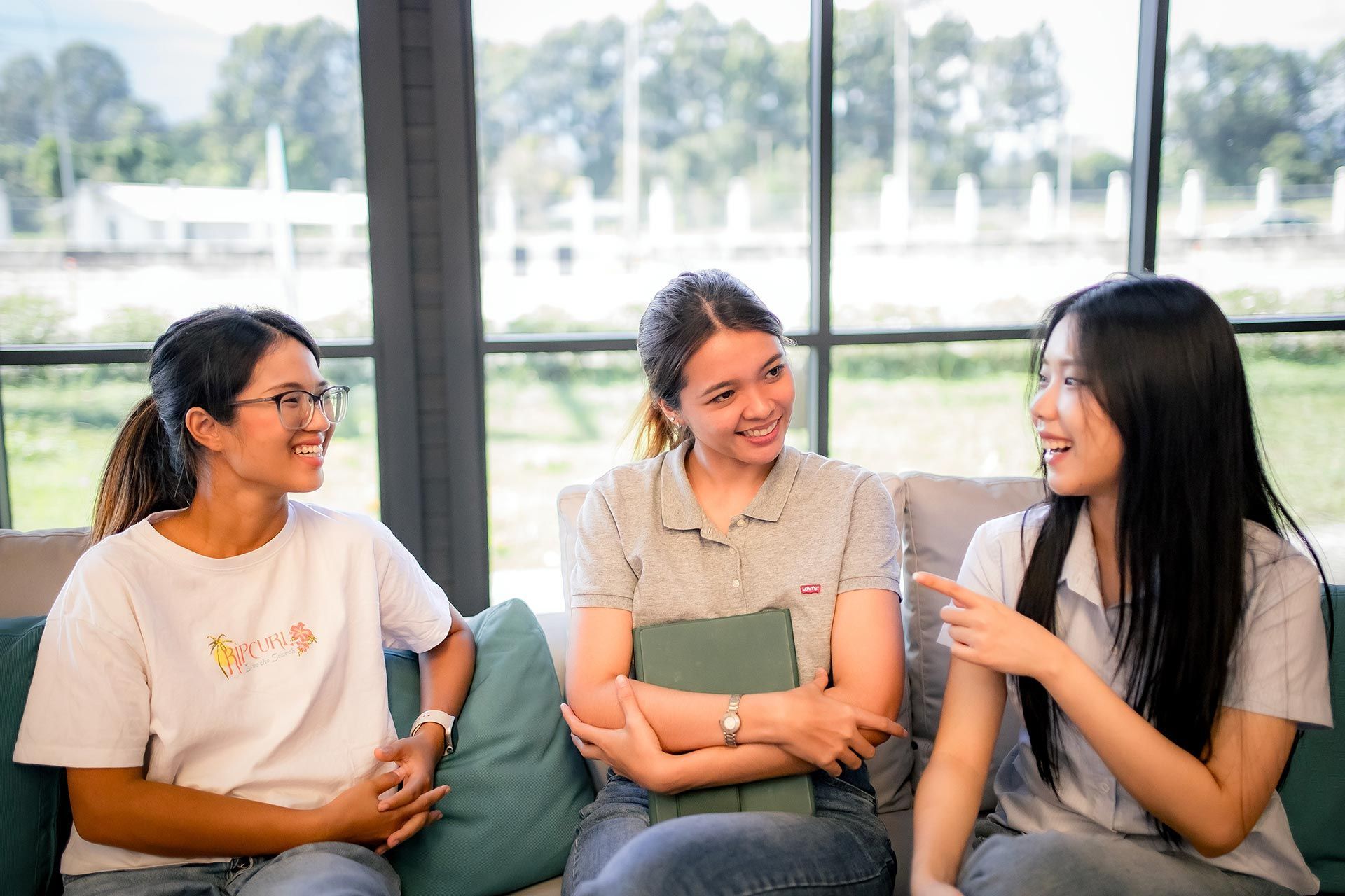 Three women from Green Light Studio re sitting on a couch talking to each other