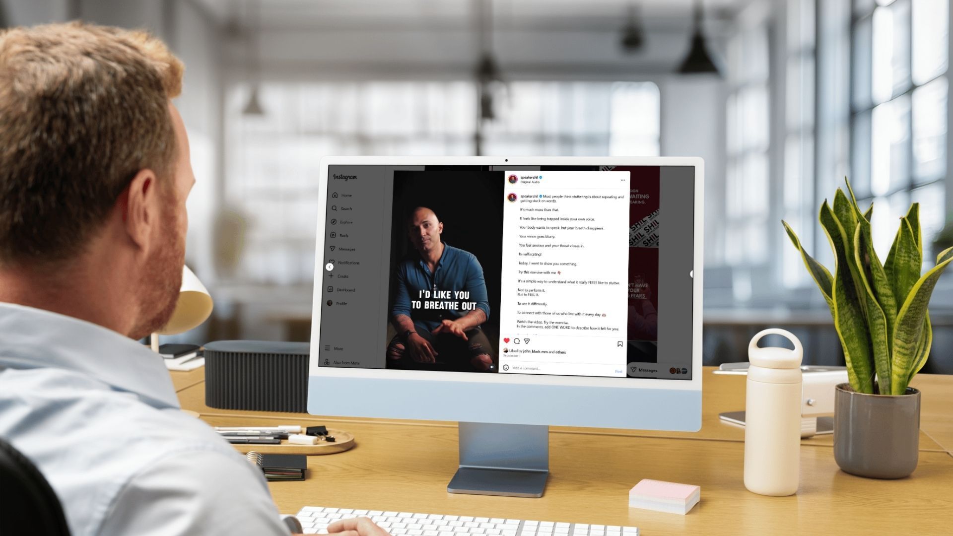 Man looking at computer screen displaying a social media post with a photo and text, in an office setting.