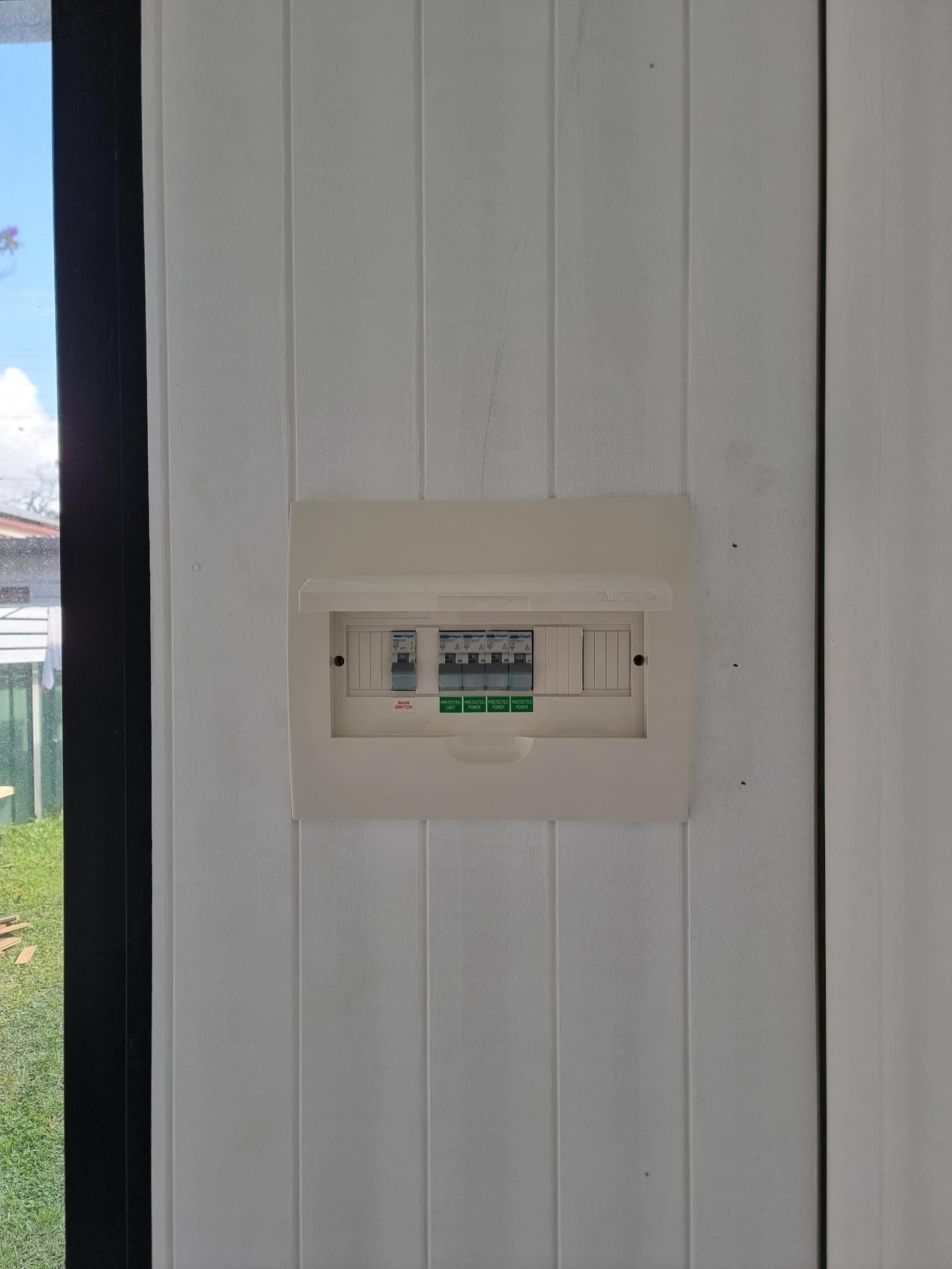 A White Electrical Box Is Hanging On A White Wall Next To A Window — Licence To Spark In Lake Macquarie, NSW