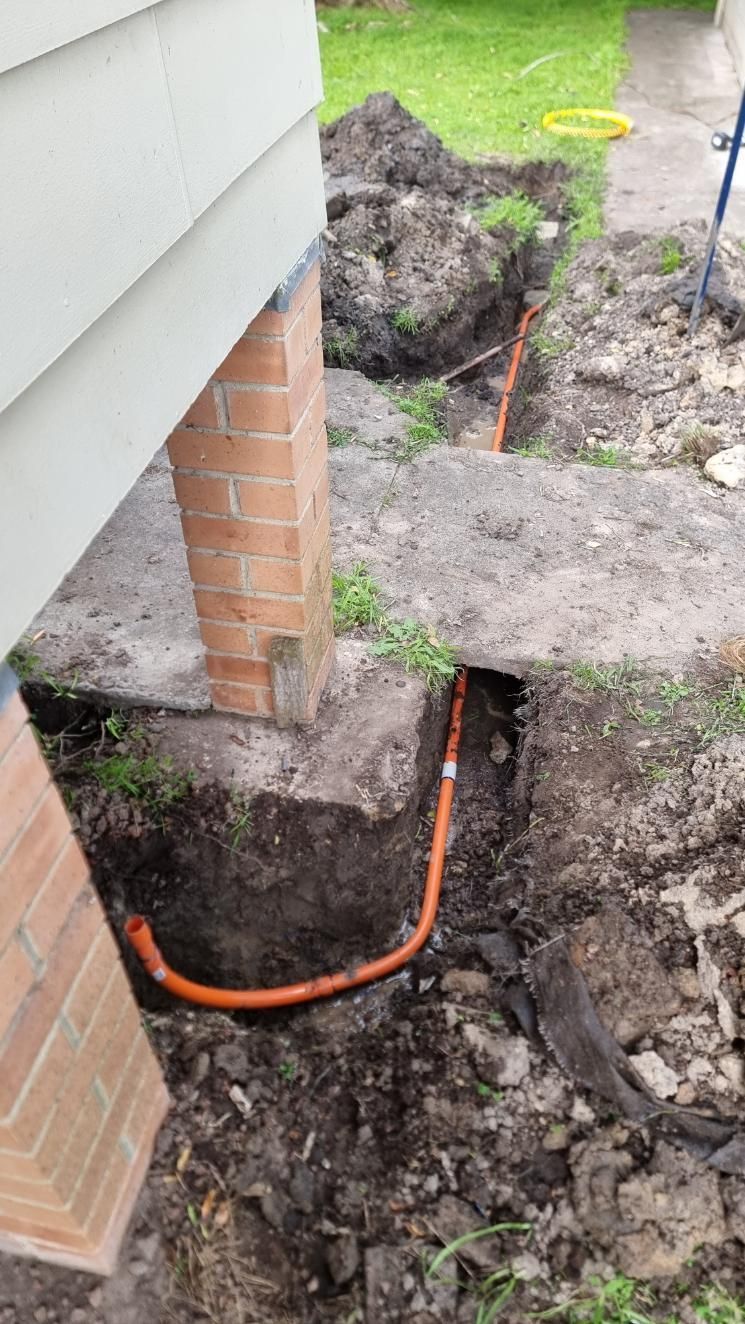 A Person Is Digging A Hole In The Ground Next To A House — Licence To Spark In Gosford, NSW