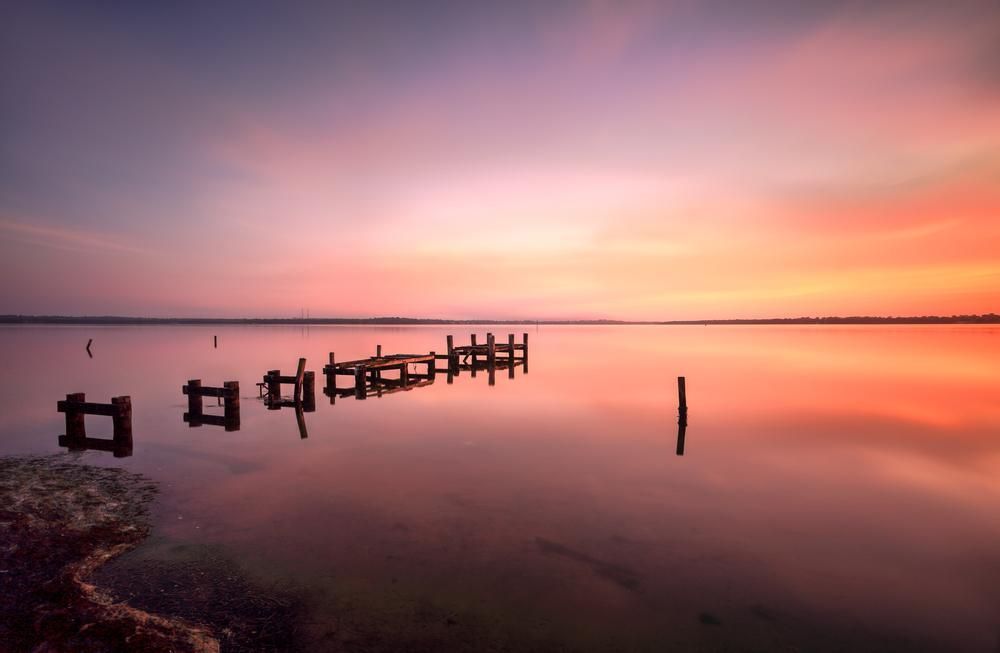 A Sunset Over A Lake With A Dock In The Water — Licence To Spark In Wyoming NSW