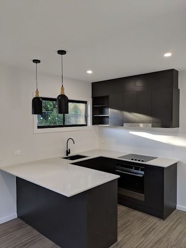 A Kitchen With Black Cabinets And A White Counter Top — Licence To Spark In Wyong, NSW