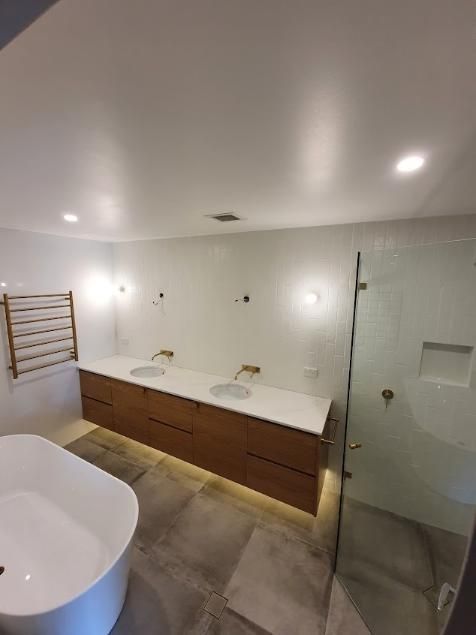 A Bright Light Bub In The Bathroom With Two Sinks And A Bathtub — Licence To Spark In Berkeley Vale, NSW