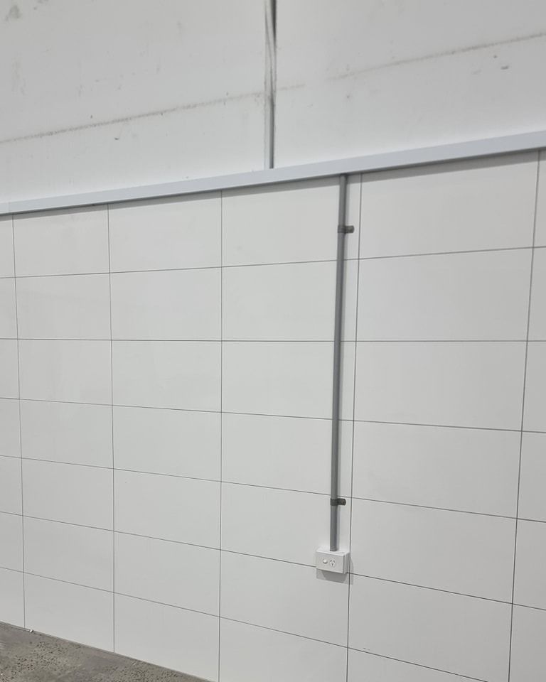 A White Tiled Wall With A Electrical Outlet On It — Licence To Spark In Wyong, NSW