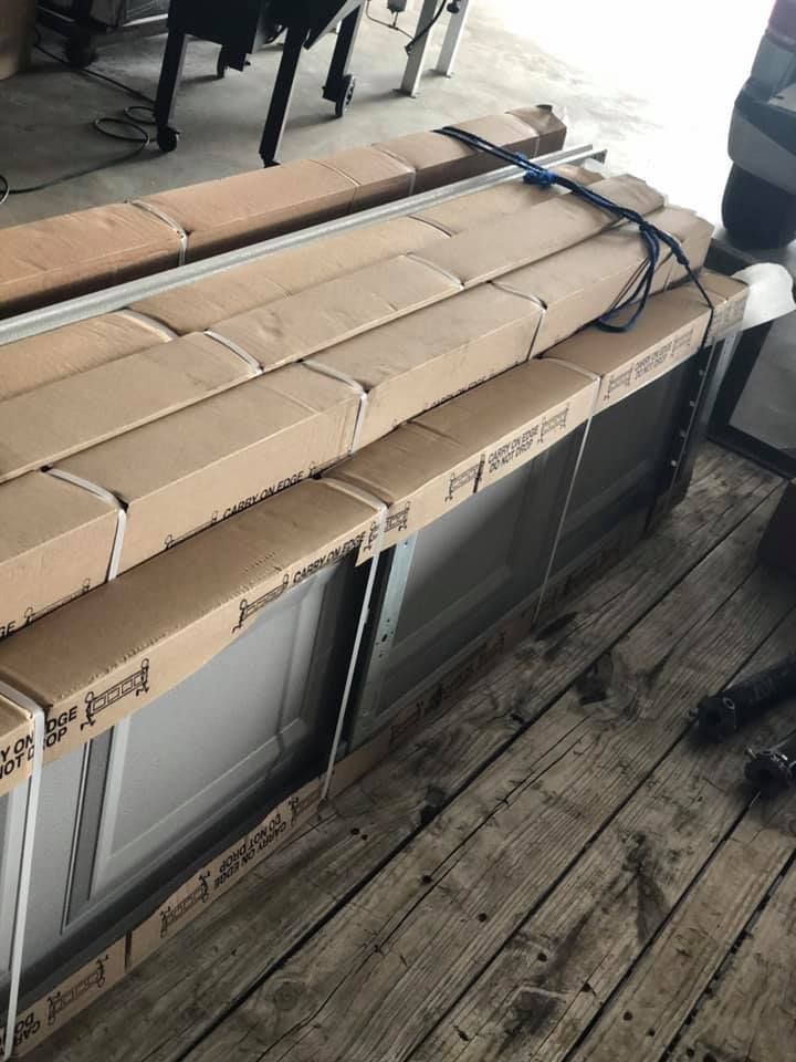 Cardboard-wrapped windows and framing on a wooden surface, ready for installation.