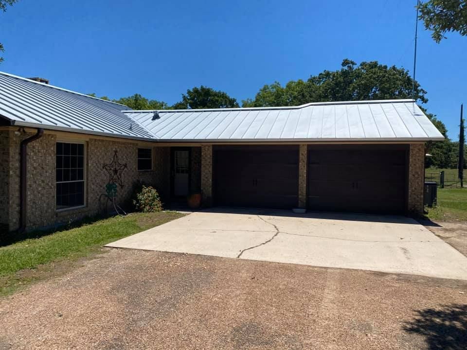 A one-story house with a metal roof and a two-car garage under a blue sky.