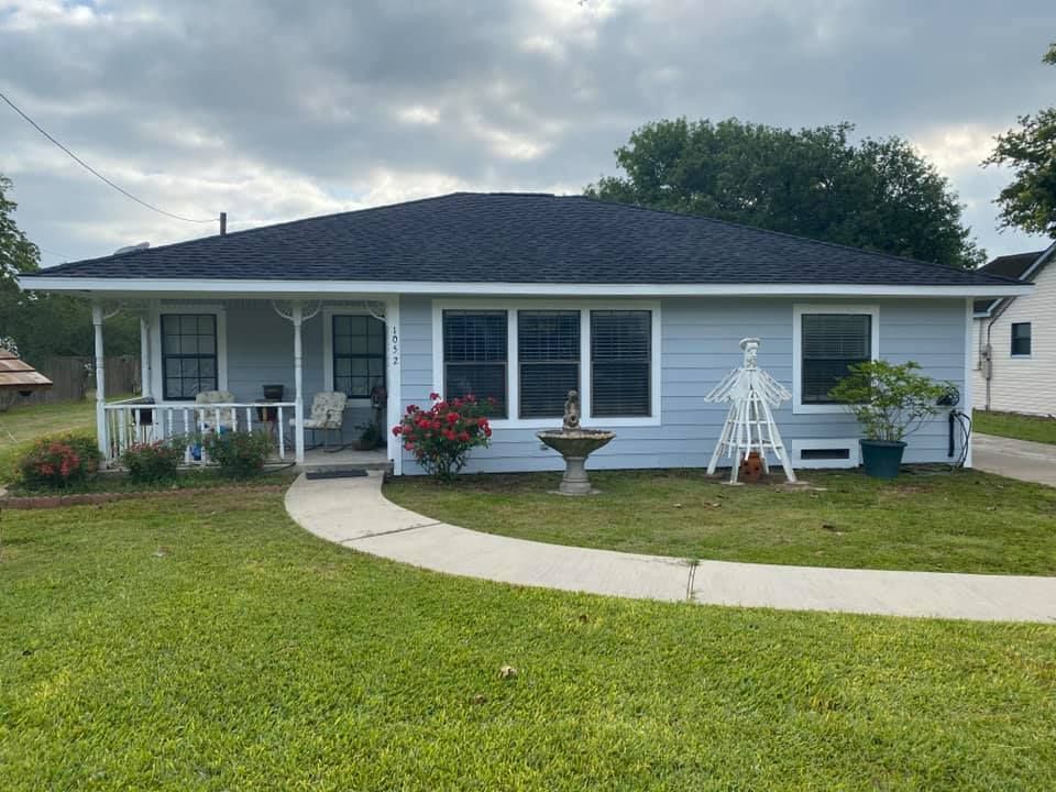 Light blue house with dark roof, small porch, and walkway on green lawn.
