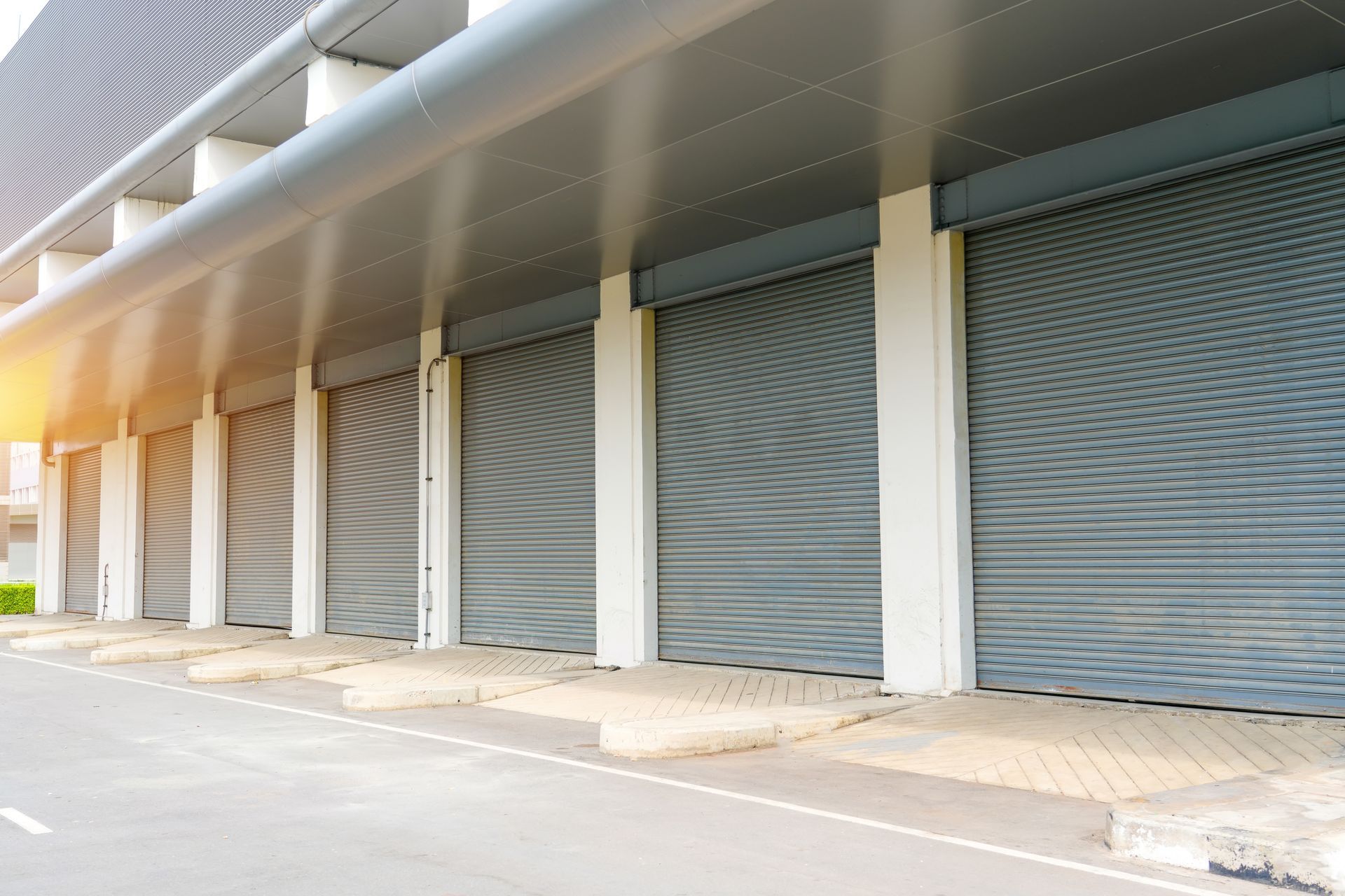 Row of closed gray roller shutter doors in a commercial building.