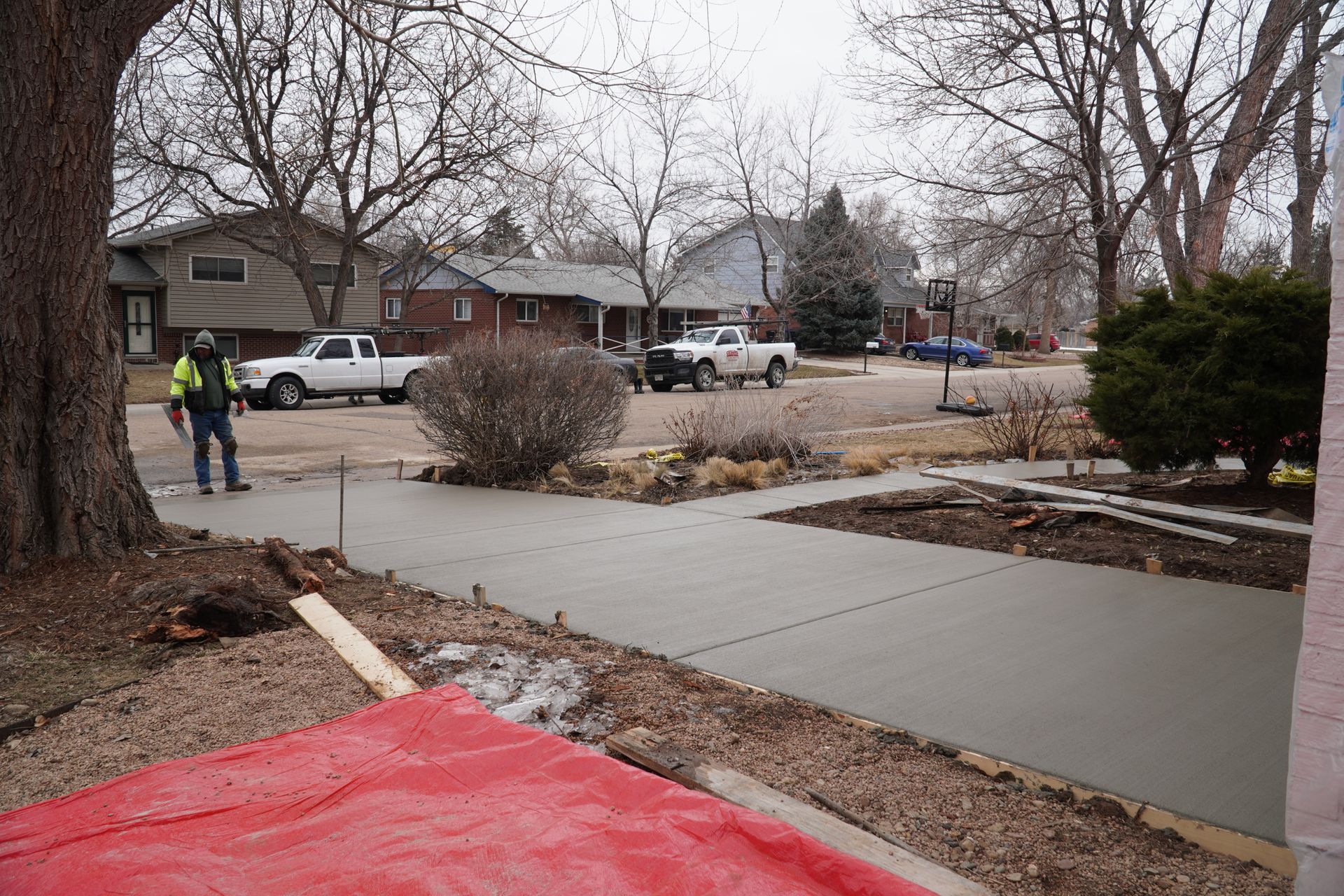 A modern, light gray one-story house with a long concrete driveway, and a wood fence on both sides.