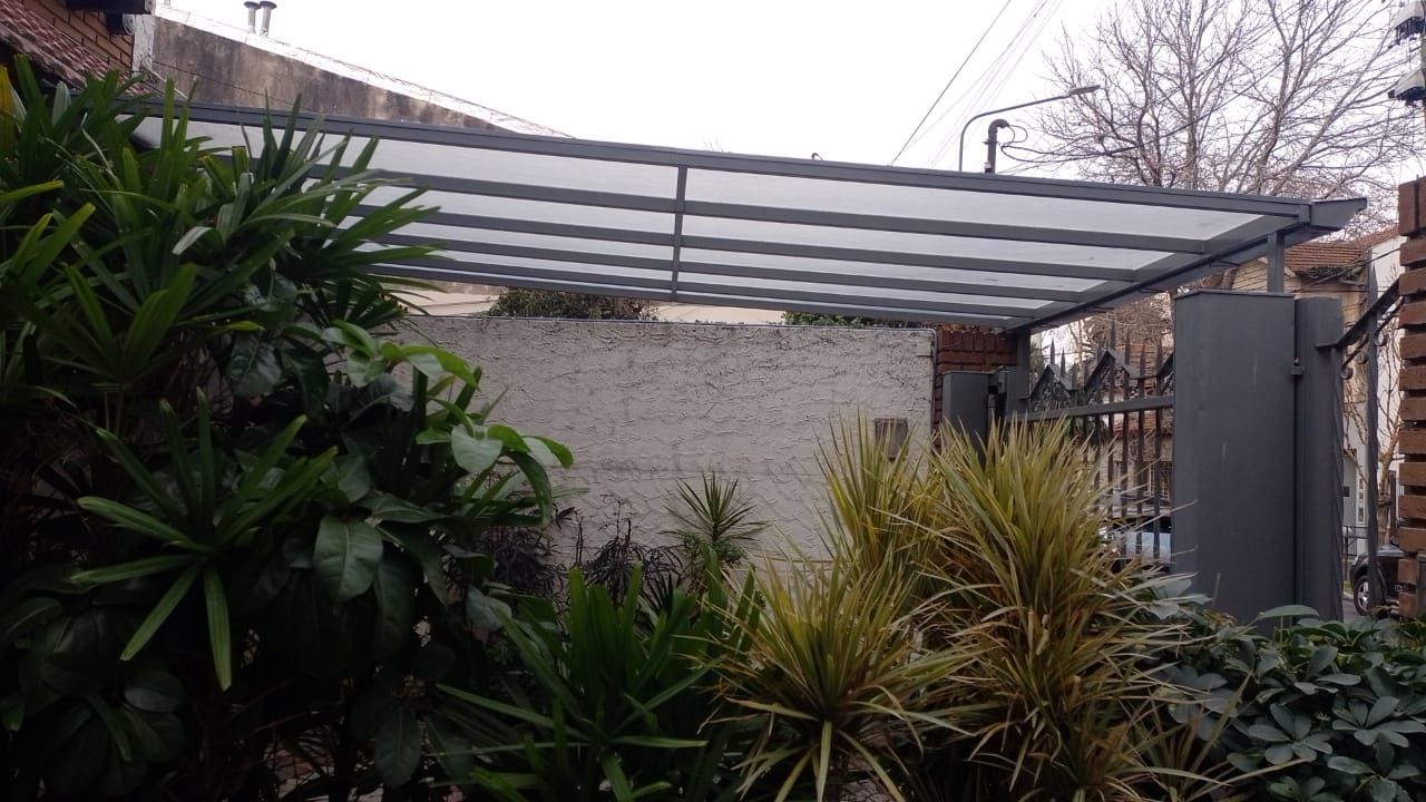 Una valla con un dosel encima está rodeada de árboles y arbustos.