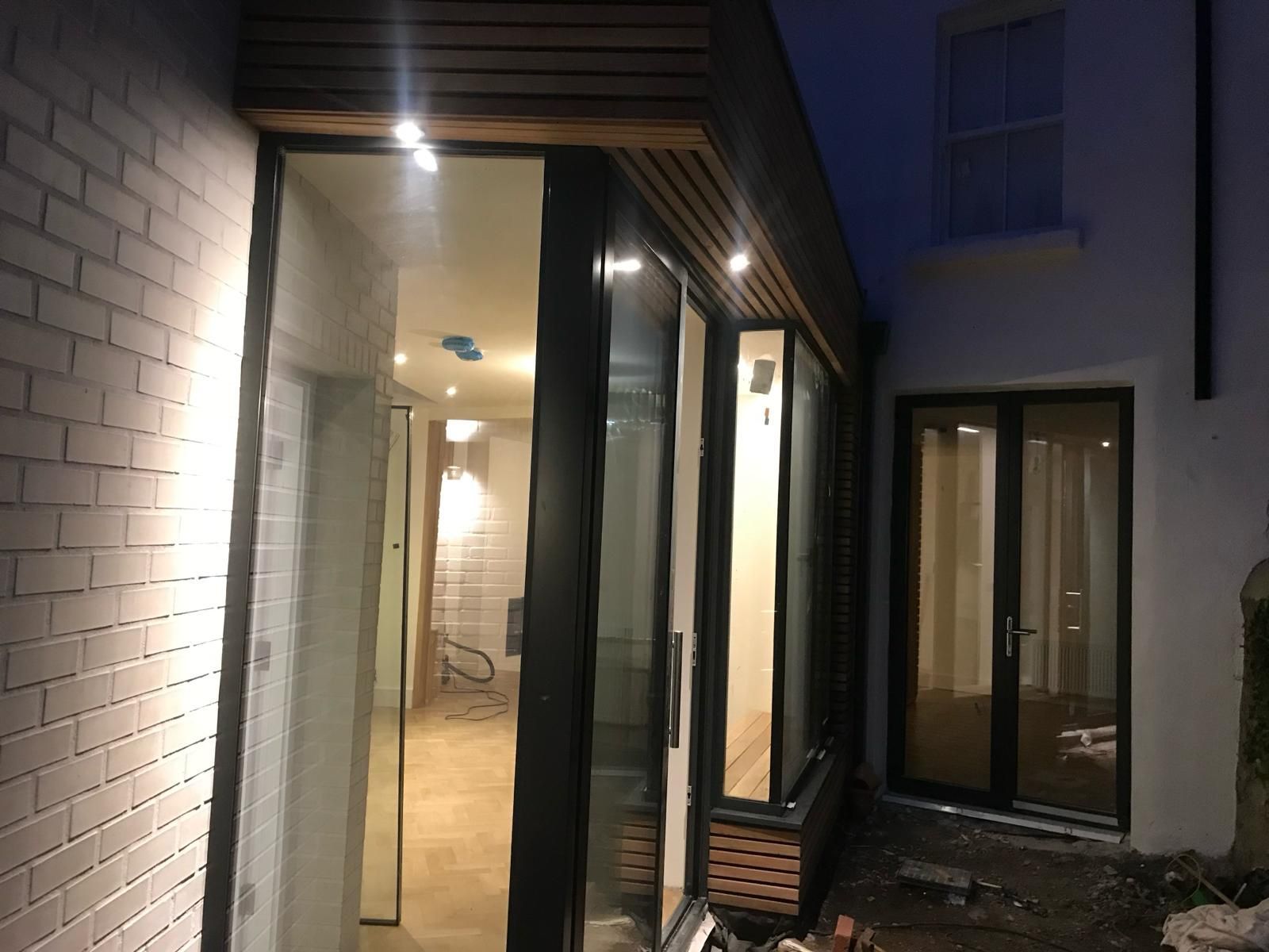 a house with a lot of windows and doors is lit up at night .