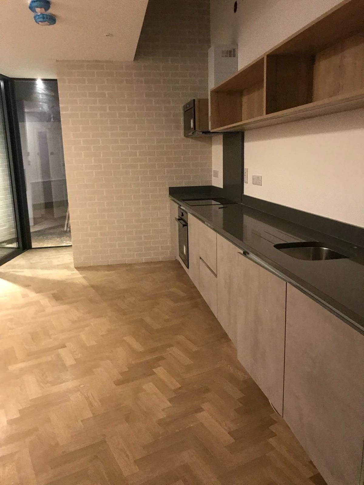 a kitchen with a wooden floor and a brick wall