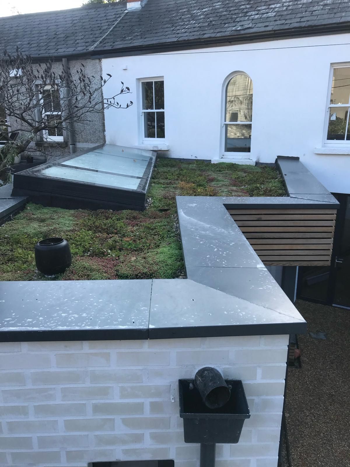 a white house with a green roof and a brick wall