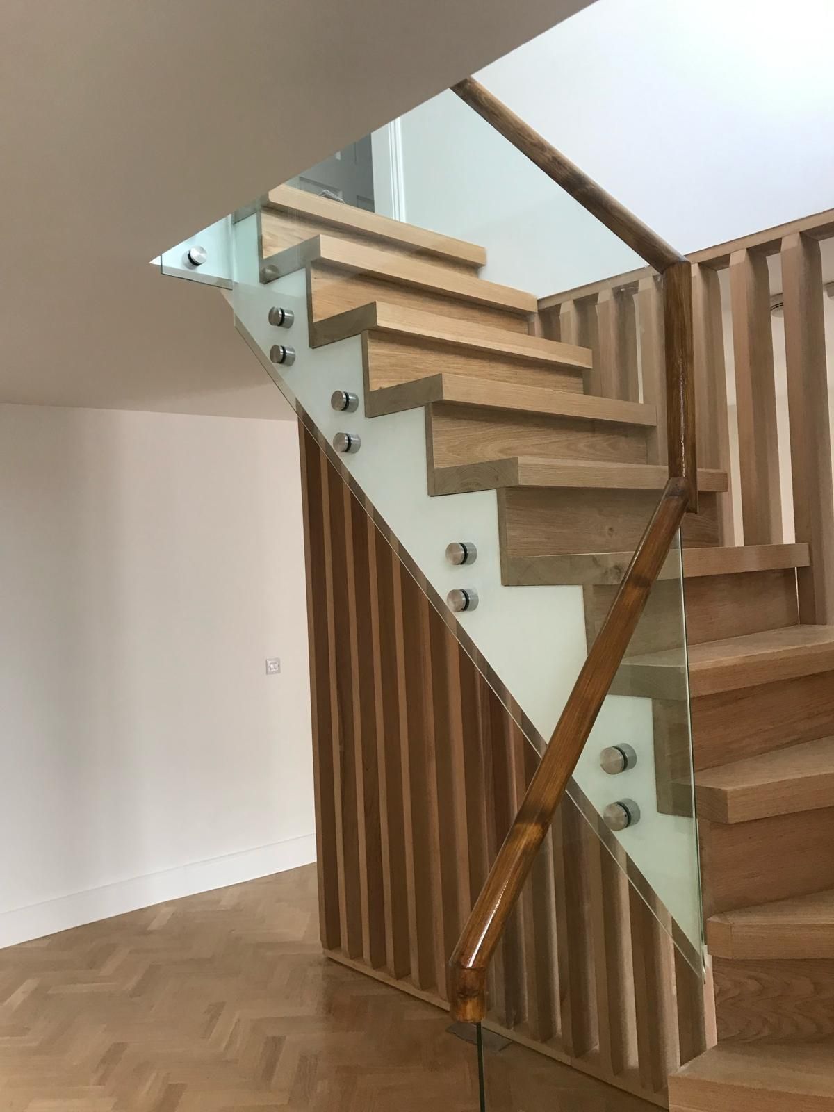 a wooden staircase with a glass railing in a room .