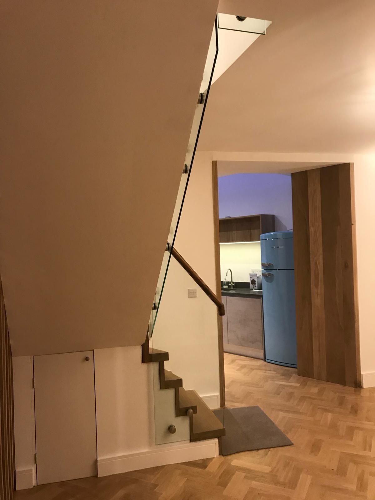 a staircase with a glass railing and a blue refrigerator in the background