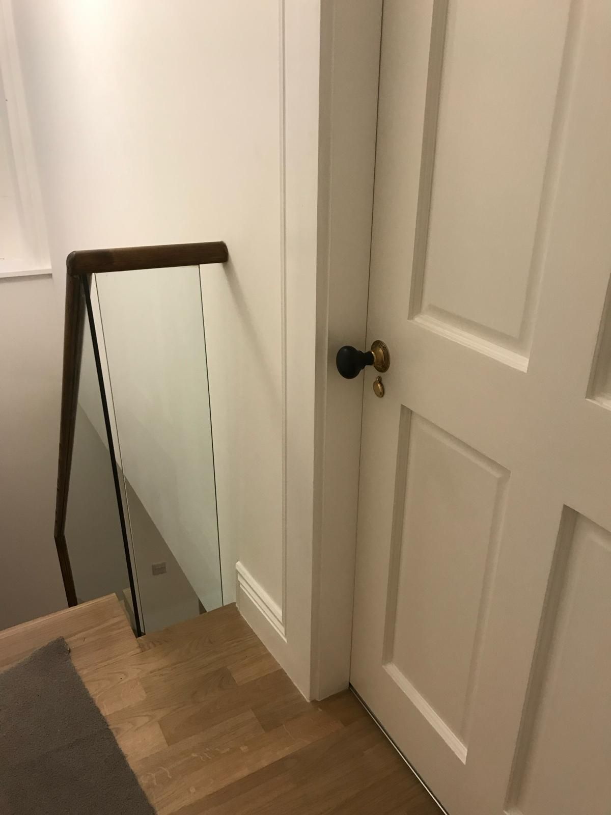 a white door is next to a staircase with a glass railing .