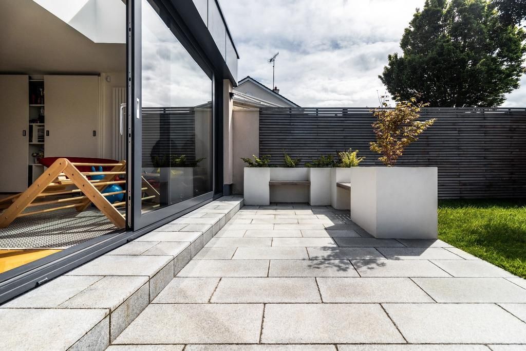 a patio with a bench and planters in the backyard of a house