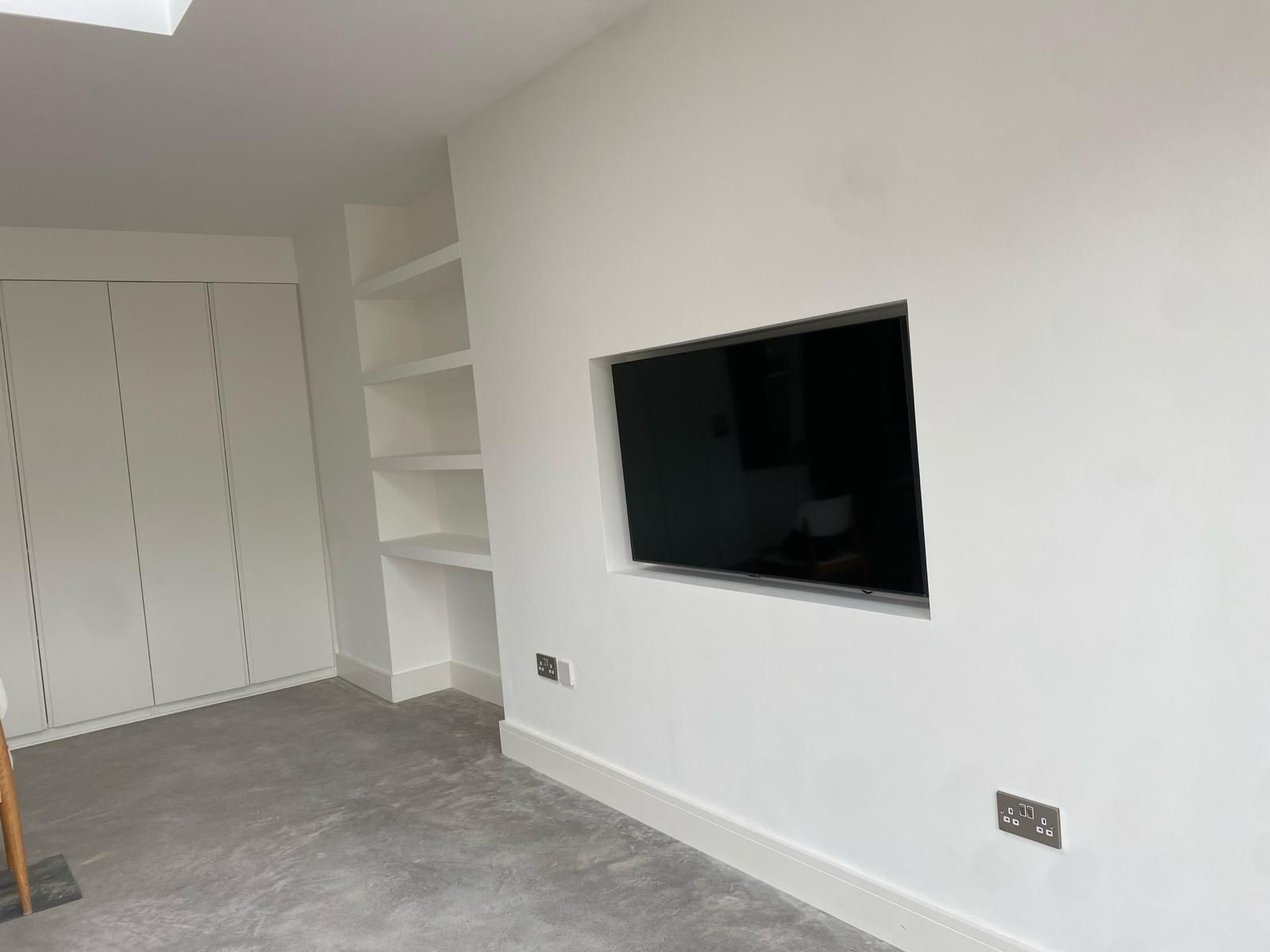 a living room with a flat screen tv mounted on the wall .