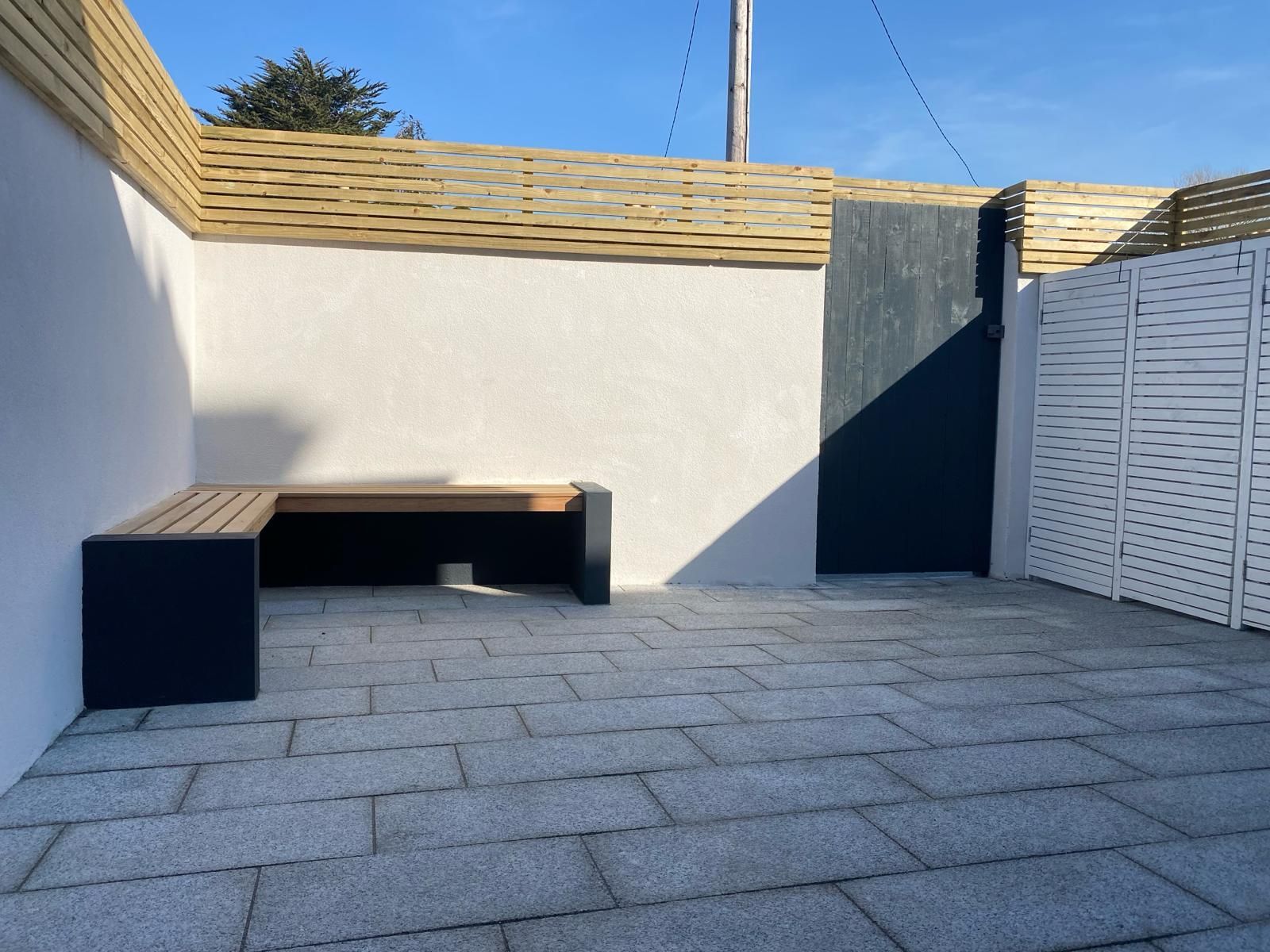a patio with a bench and a fence in the background