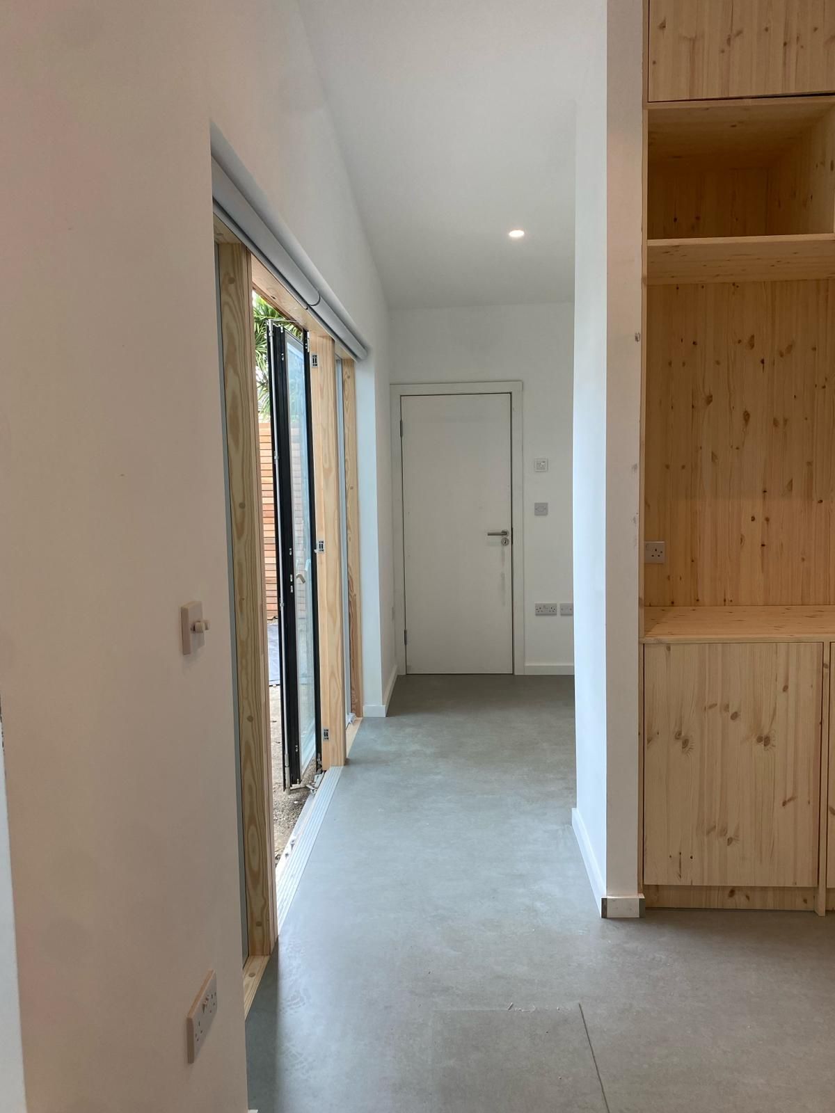 a hallway in a house with wooden cabinets and sliding glass doors .