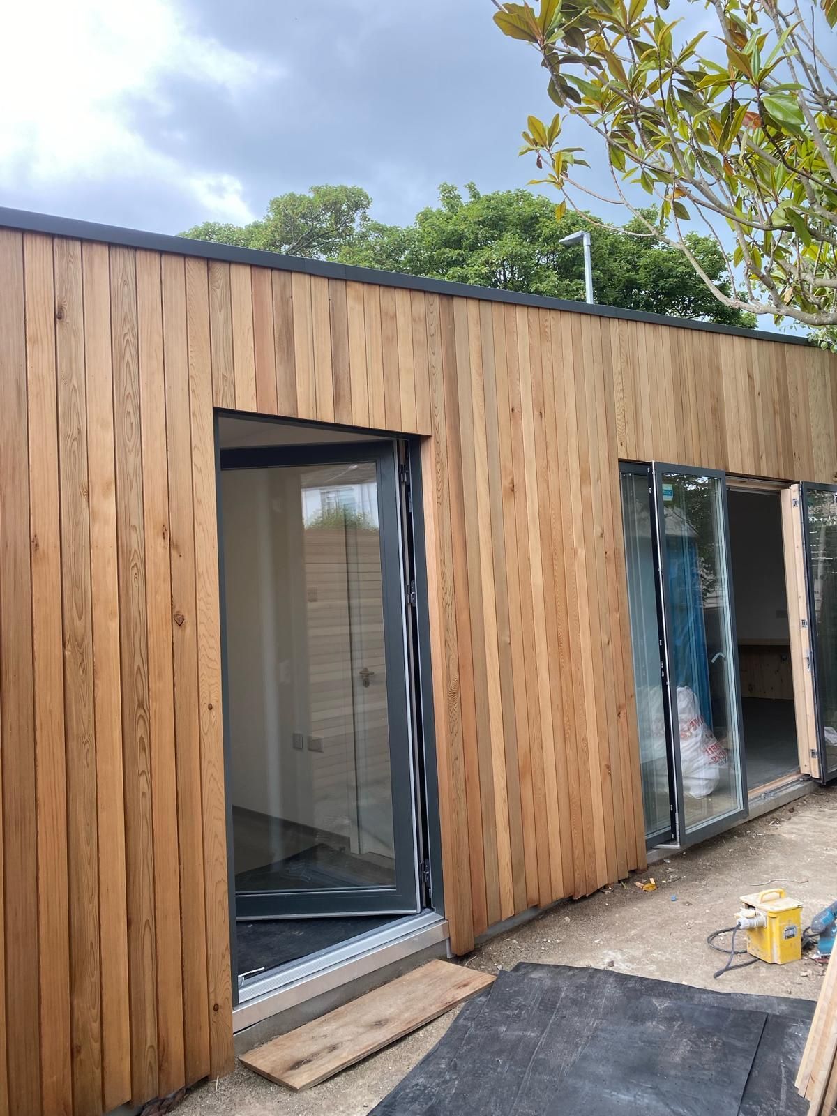 a wooden building with sliding glass doors is being built .