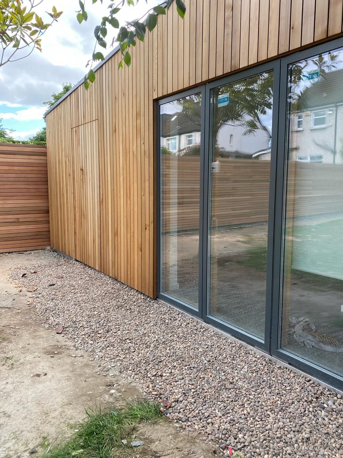 a wooden building with a lot of windows and gravel in front of it .