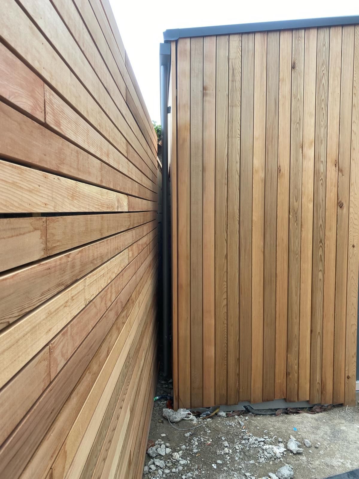 a close up of a wooden fence next to a building .