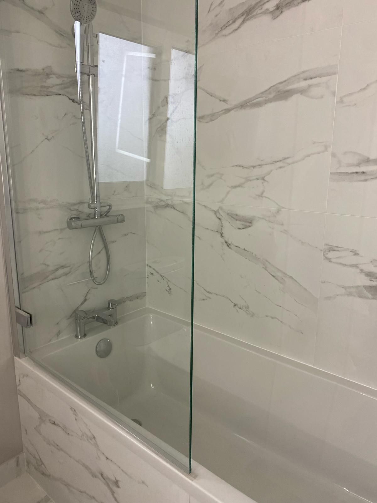 a bathroom with a bathtub and a shower stall with a glass door .