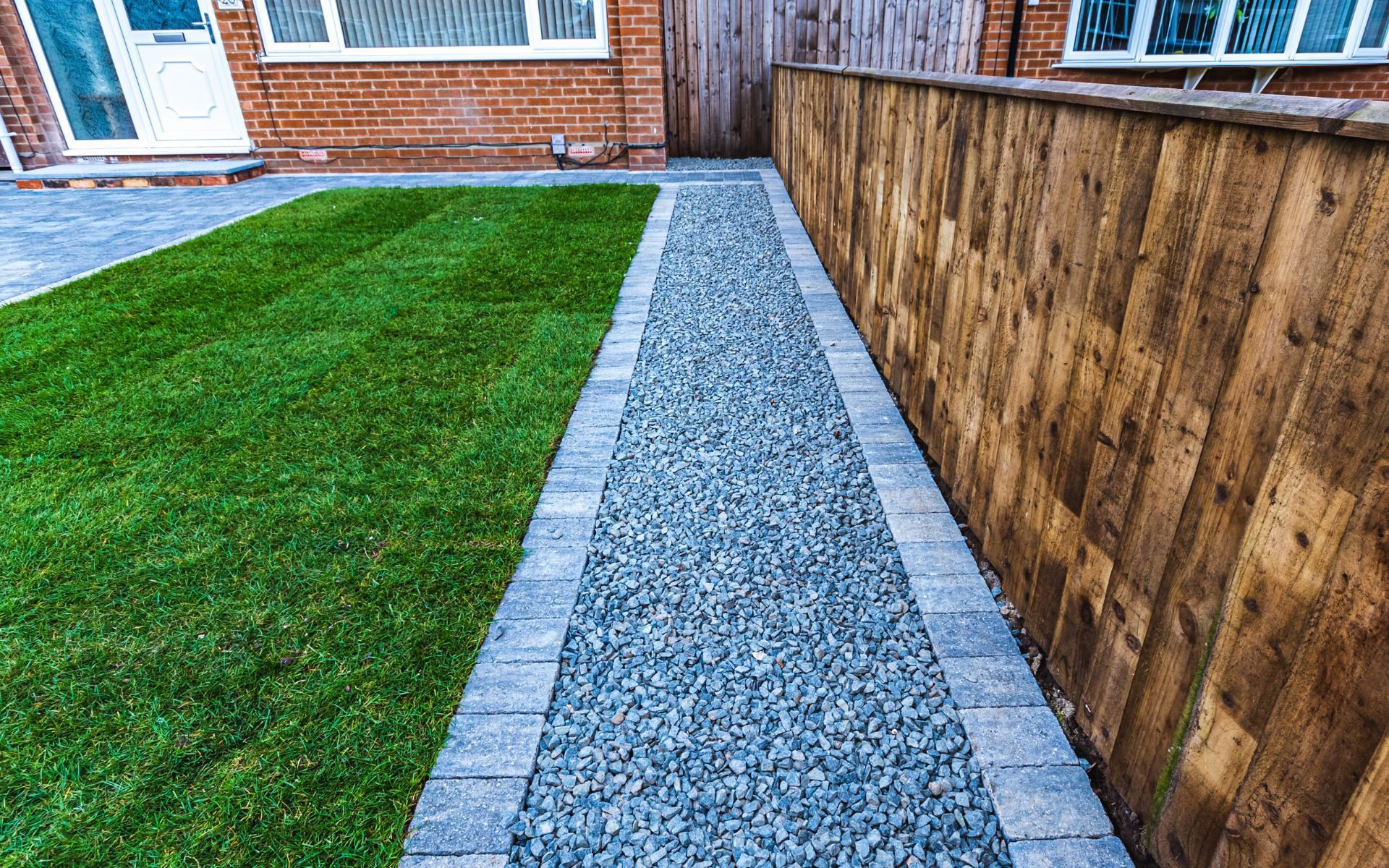 a walkway leading to a house with a wooden fence .