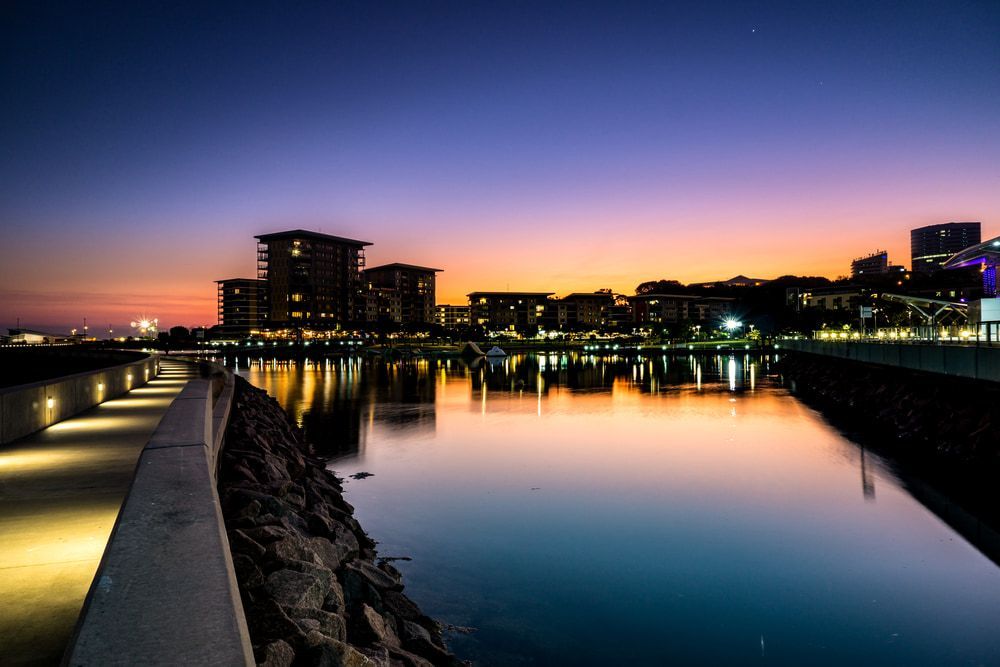 A Sunset Over A Body Of Water With Buildings In The Background — Chris's Automotive & Marine Electrics In Darwin, NT