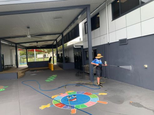 A Man Is Spraying Water On A Colorful Drawing On The Ground — Tailored Services in Mackay Harbour, QLD