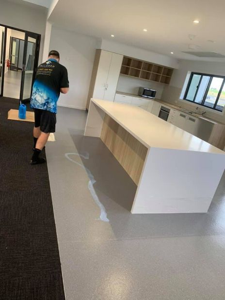 A Man Is Standing In A Kitchen With A Large Island — Tailored Services in Mackay Harbour, QLD