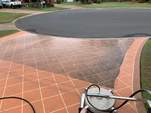 A Person Is Cleaning A Driveway With A Machine — Tailored Services in Mackay Harbour, QLD