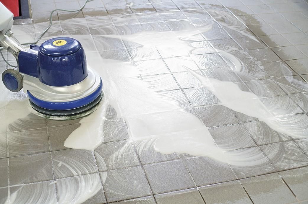 A person is cleaning a tiled floor with a machine — Tailored Services in Mackay Harbour, QLD