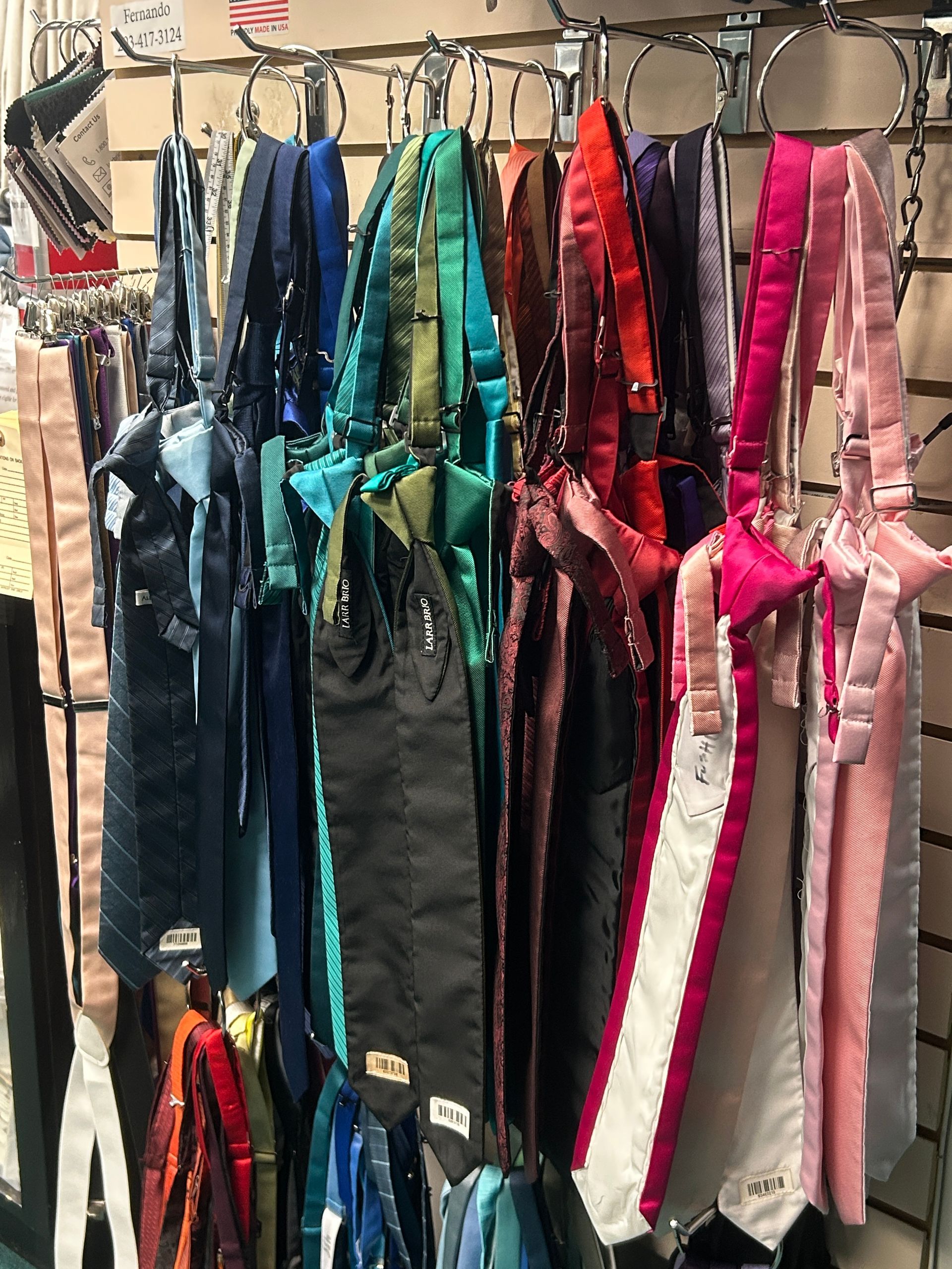 Row of shiny colorful satin costumes on hangers, with teal, black, red, and pink outfits displayed together