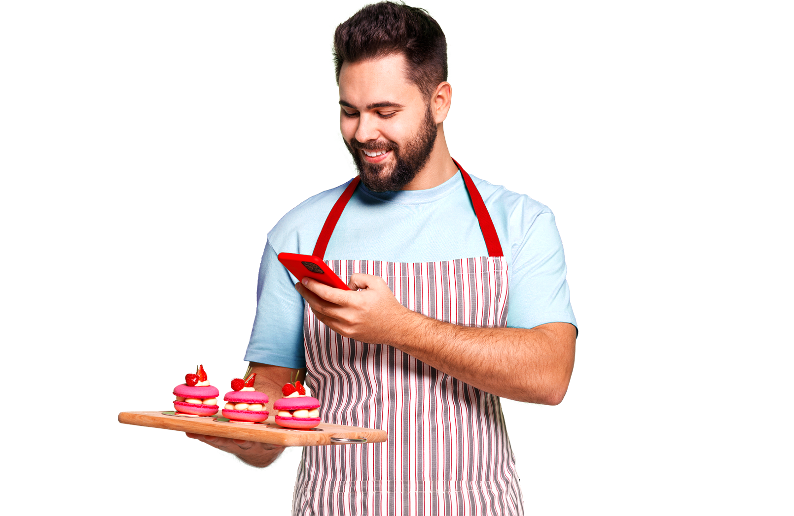 Um homem de avental está segurando uma bandeja de cupcakes e olhando para o telefone.