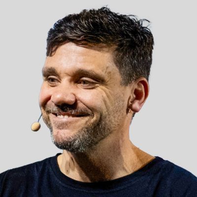 Um homem com um microfone no ouvido está sorrindo.
