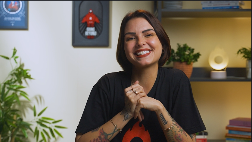 Uma mulher de camisa preta está sorrindo com as mãos cruzadas