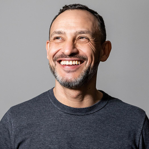 Um homem com barba está sorrindo e olhando para cima.