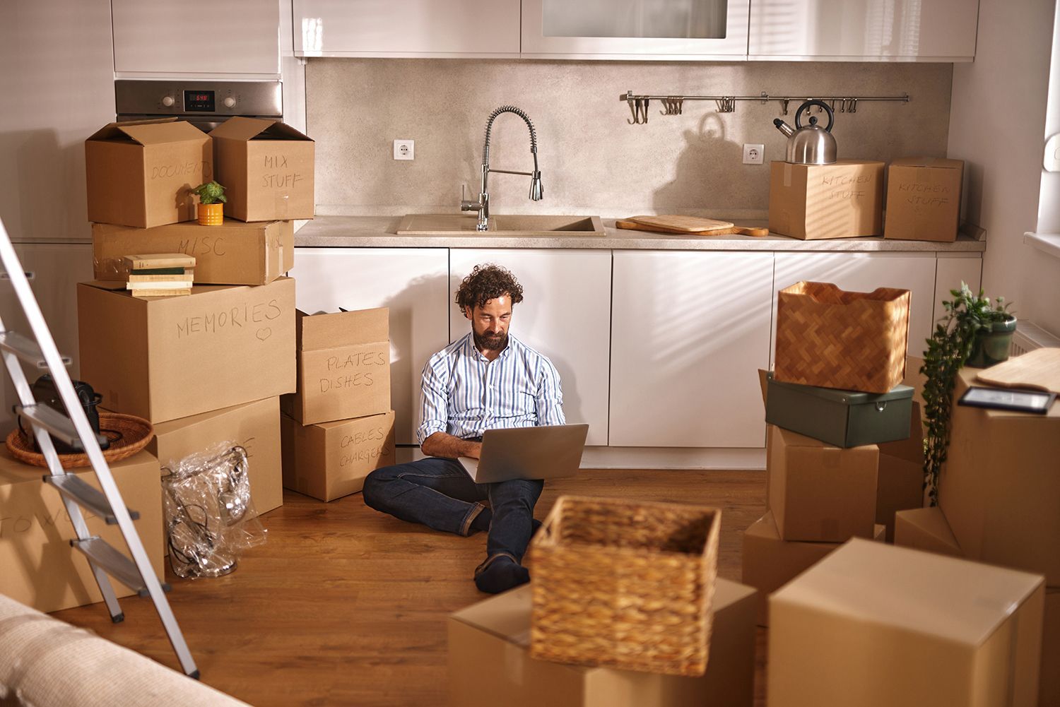 A man sits on the floor of a newly moved-in kitchen. A man sits on the floor of a newly moved-in kitchen.