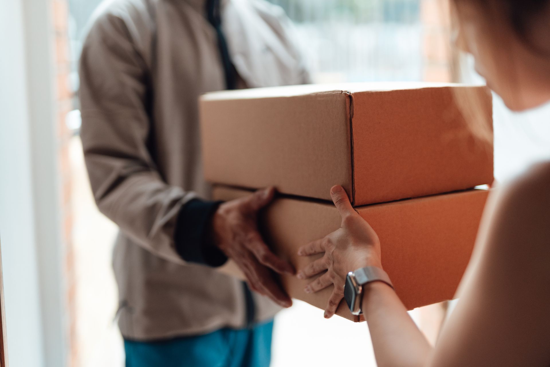 Closeup of delivery person handing in a package to customer | Reliance Paper Closeup of delivery person handing in a package to customer | Reliance Paper