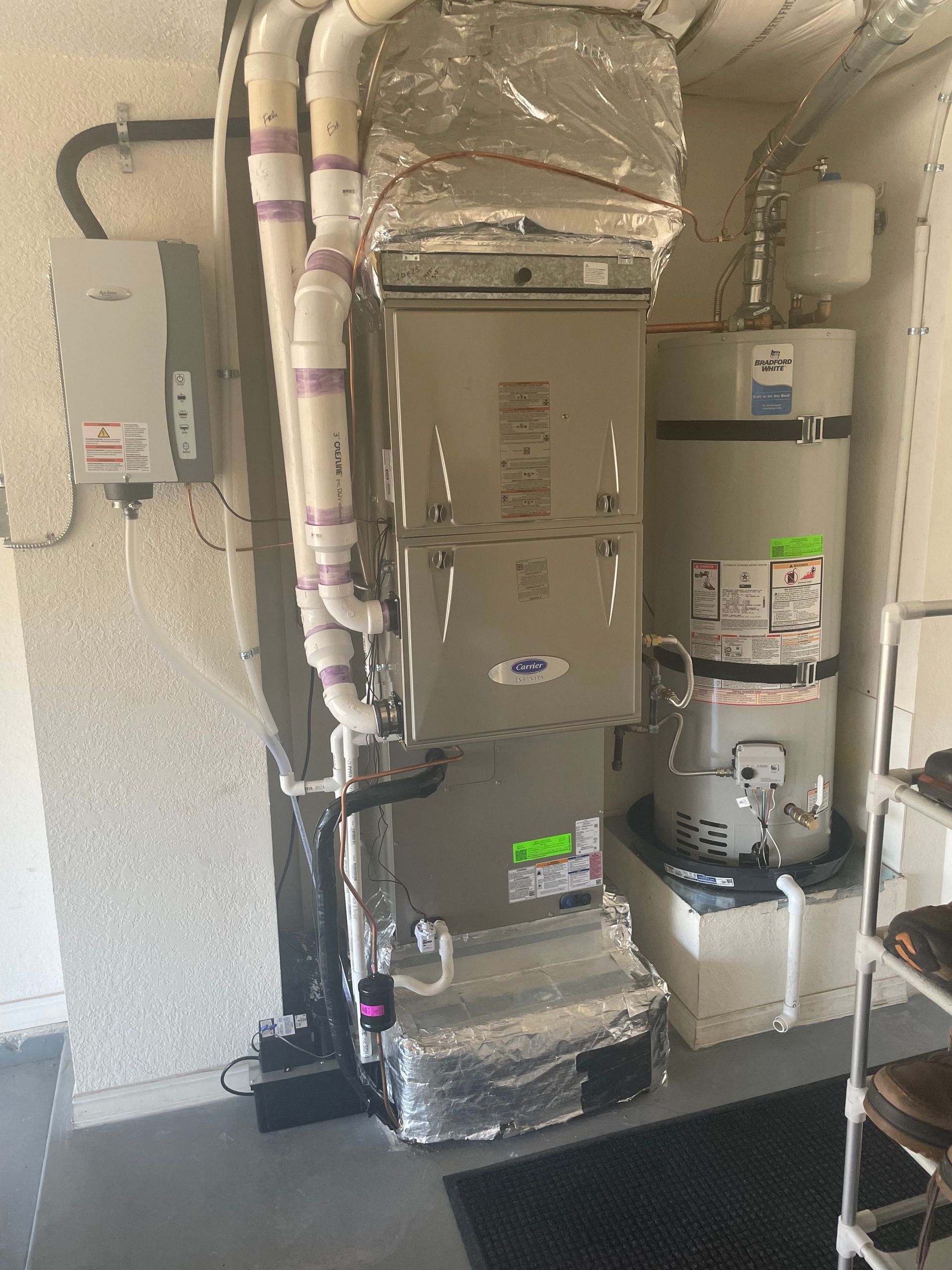 A man is sitting on the floor fixing an air conditioner.